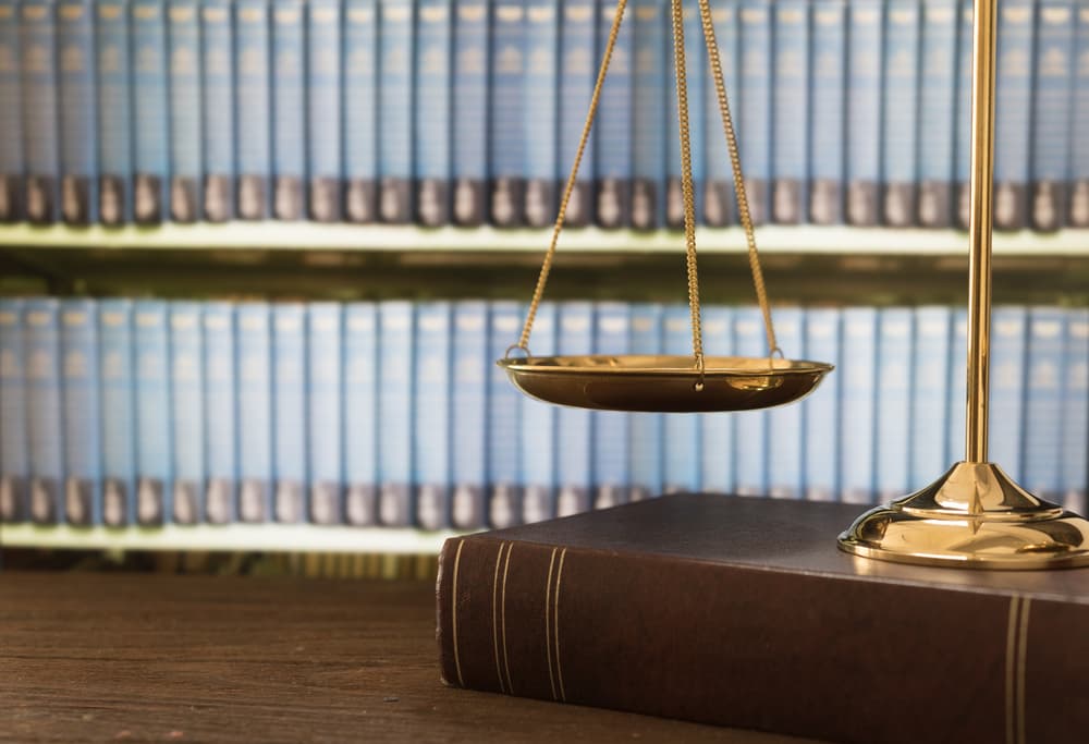 Scales of justice on law books in a law firm library, symbolizing the importance of verifying legal licenses and credentials.